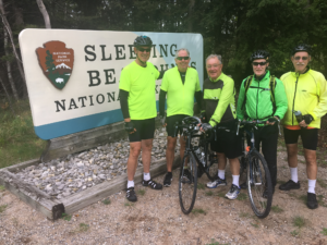 Cyclists pose by National Park Sign on Grand Traverse Tour